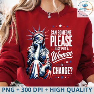 以下が含まれることがあります： アメリカ国旗柄のサングラスをかけた自由の女神像のグラフィックがプリントされた、ダークレッドのクルーネックトレーナー。テキストには「CAN SOMEONE PLEASE JUST PUT A WOMAN IN CHARGE?」と書かれており、赤、白、青の星と線がデザインされています。