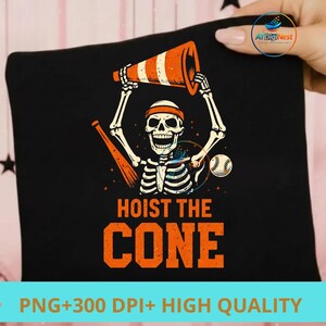 May include: Black t-shirt featuring a skeleton holding an orange and white traffic cone, with a baseball and bat. The text "HOIST THE CONE" is in orange. A fun, Halloween-themed design.