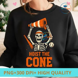 May include: Black sweatshirt with a skeleton graphic holding an orange and white traffic cone. The text "HOIST THE CONE" is in orange block letters. A baseball and a baseball bat are also in the design. The bottom of the sweatshirt reads "PNG+300 DPI+ HIGH QUALITY".