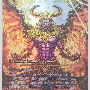 May include: A holographic trading card featuring "Ob Nixilis, Captive Kingpin." The card depicts a muscular demon with horns, wings, and fiery background. Text includes "Legendary Creature - Demon," "Flying, trample," and game instructions. The card's power/toughness is 4/3.