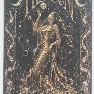 May include: A rectangular card featuring the word TREASURE in gold lettering at the top. The artwork depicts a figure in a flowing gold gown reaching towards a glowing diamond. The design includes holographic accents, celestial motifs, and stars.