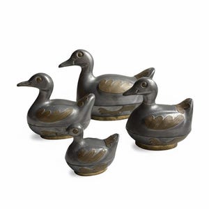 May include: A set of four decorative duck figurines in varying sizes. The ducks are primarily gray with gold-colored accents on their wings. The ducks have a smooth, metallic finish and are arranged on a white background.