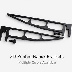 Peut inclure: Deux supports Nanuk noirs imprimés en 3D avec un design unique, comportant plusieurs sections découpées et une vis. Les supports sont conçus pour maintenir des objets et sont disponibles en plusieurs couleurs.