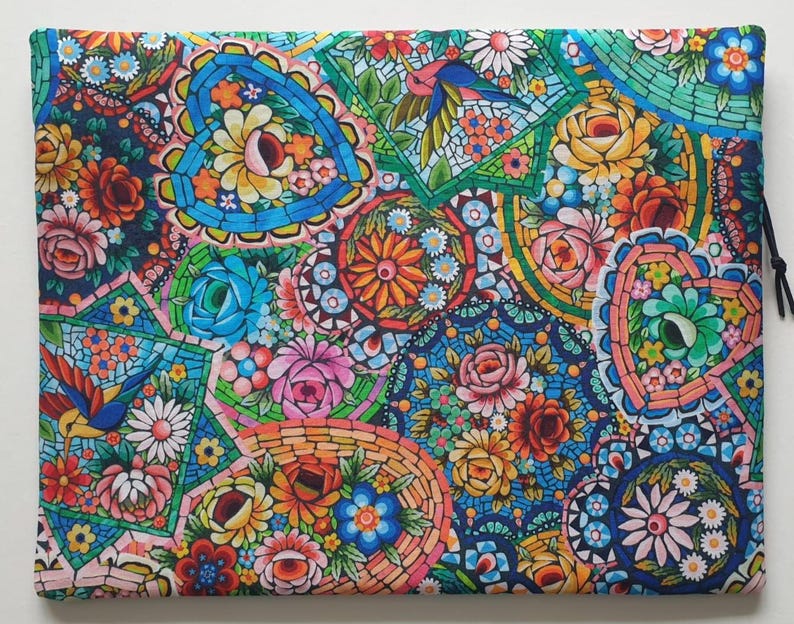May include: A colorful, floral-patterned pouch with a drawstring closure. The design features a mosaic-like arrangement of flowers, hearts, and birds in shades of blue, pink, orange, and green. The pouch is rectangular and appears to be made of fabric.