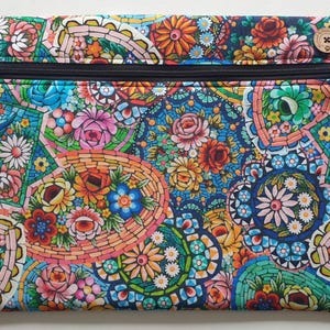 May include: A rectangular zippered pouch with a vibrant floral mosaic pattern. The design features a variety of colorful flowers in shades of pink, orange, blue, and green. A wooden button with a cross design is on the top right corner.
