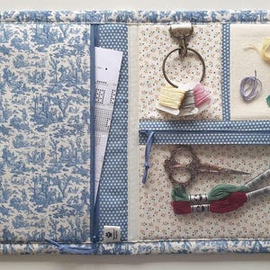 Astuccio/pochette per accessori da ricamo a punto croce Maison Sajou. 2 tasche con cerniera, clip per i fili, scomparto per i fili. Dimensioni da aperto: 45,7 x 30,5 cm. Tessuto Toile de Jouy.