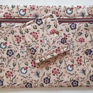 May include: A rectangular fabric pouch with a zip closure and a smaller square fabric pouch with a snap fastener, both featuring a beige background with a repeating floral pattern in shades of red, dark blue, and green, and a wooden button detail.