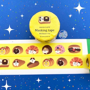 May include: Yellow masking tape roll with a cat and food design. The tape is 20mm wide and 7m long. The tape features illustrations of cats inside various food items like sandwiches and pastries. The background is blue with white stars.
