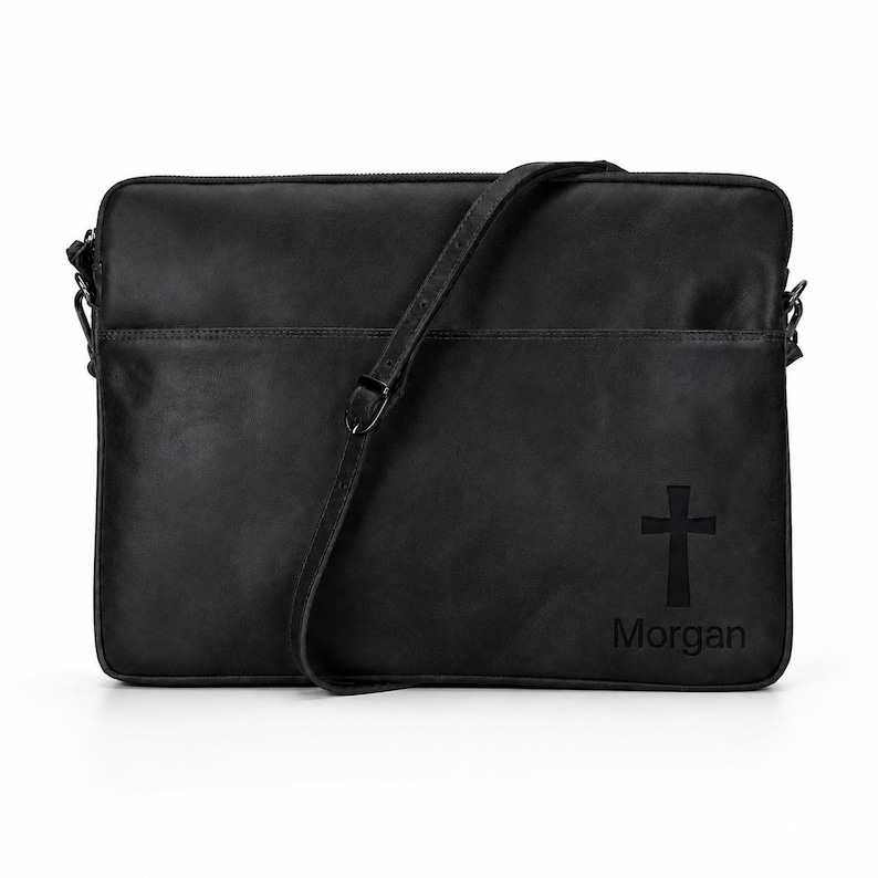 May include: A black rectangular laptop bag with a smooth finish, featuring an adjustable shoulder strap and a top zipper closure. The bottom right corner displays a debossed cross symbol positioned directly above the name Morgan in black text.
