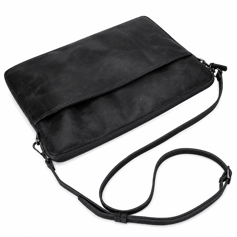 May include: A rectangular black shoulder bag with a smooth, matte finish. The bag features a zippered main compartment, a front flap pocket, and a thin, adjustable black shoulder strap attached with dark metal hardware on both sides.