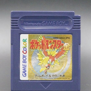 May include: A purple Game Boy Color cartridge with a gold label featuring a red and yellow bird with the text "ポケットモンスター 金" (Pocket Monsters Gold) and "ゲームボーイ & カラー共通" (Game Boy & Color Compatible).