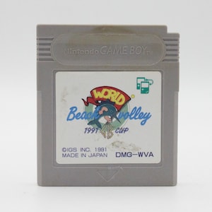 May include: A gray Game Boy cartridge with a colorful label featuring a cartoon dolphin and the text "World Beach Volley 1991 Cup". The label also includes the text "DIGS INC. 1991 MADE IN JAPAN DMG-WVA".