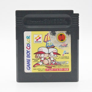 May include: A black Game Boy Color cartridge with a yellow, red, and white label. The label features two cartoon characters playing baseball and the text "KONAMI" and "NPB".