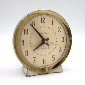 May include: A gold-colored Westclox alarm clock with a white face and black hands. The clock face has black numbers and the text "Big Ben" and "WESTCLOX".
