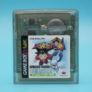 May include: A clear Game Boy Color cartridge with a green label. The label features a cartoon character with a red shirt and a blue hat, along with a blue and white creature. The text on the label reads "KUWAGATA VERSION" and "ゲームボーイカラー専用".