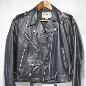 May include: Black leather motorcycle jacket with a zipper closure, multiple pockets, and a belt at the waist. The jacket has a label that reads "Park E."
