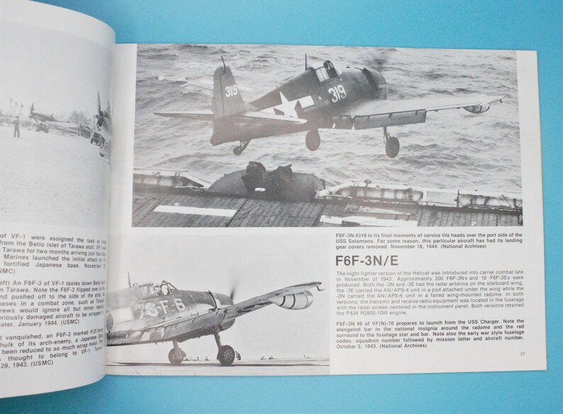 May include: A black and white photograph of a Grumman F6F-3N Hellcat fighter plane taking off from an aircraft carrier. The plane has the number 319 painted on the side. The photo is from World War II.
