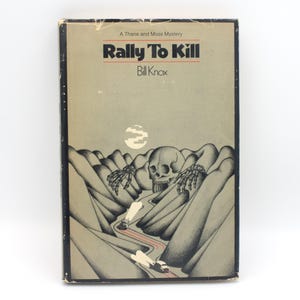 May include: A vintage book titled "Rally To Kill" by Bill Knox. The cover features a grayscale illustration of a skull, skeletal hands, and a winding road through a mountain range. The book is part of "A Thane and Moss Mystery" series.