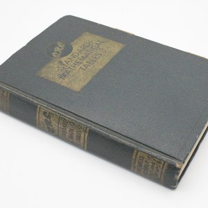 May include: A black hardcover book with gold lettering on the spine and front cover. The title is "Standard Mathematical Tables".