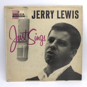 May include: Vintage vinyl record album cover for "Jerry Lewis Just Sings." The cover features a black and white image of Jerry Lewis singing into a microphone. The album title and artist name are printed in black and pink.