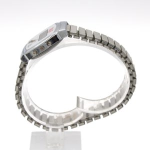 May include: A silver-tone digital wristwatch featuring a rectangular case with a white face, a small digital display, and three side buttons. The watch includes a flexible, segmented metal expansion band with a polished finish.