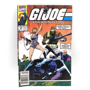 May include: A vintage comic book cover for G.I. Joe, featuring action-packed illustrations. The cover displays the title "G.I. Joe: A Real American Hero!" and the Marvel Comics logo. The artwork depicts characters with weapons and the text "INSIDE: Darklon's Forces Pursue The Joes..."