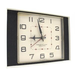 May include: Square, vintage Westclox electric clock with a cream-colored face and black numbers. The clock has black hands and a red second hand. The clock is in a black and white frame. The text "WESTCLOX electric" is printed on the face.