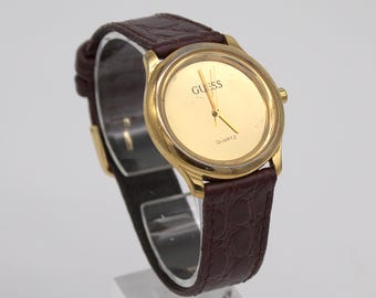 Vintage 1990s Guess watch gold tone case analog dial with gold triangle GUESS logo brown leather band cool 90s minimalist fashion