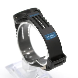 May include: Black digital sport watch with a black band. The watch face is not visible. The band has the word "SPORT" printed in blue and the words "DIGITAL - TIME" printed in blue.