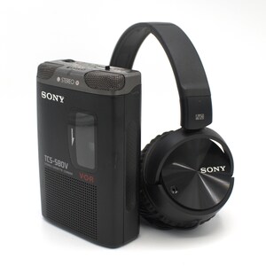 May include: A black Sony TCS-580V cassette recorder with a matching black over-ear headphone set. The recorder has the Sony logo and the word "STEREO" printed on it. The headphones are also branded with the Sony logo.