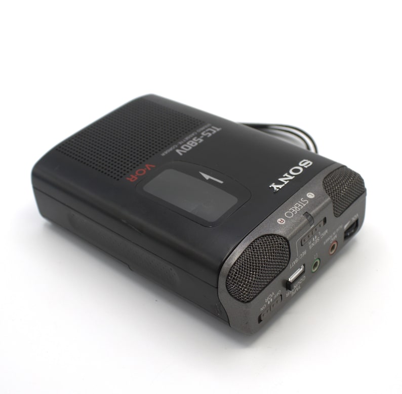 May include: Black Sony TCS-580V cassette recorder with a dark gray speaker grill and the word "SONY" in white. The recorder has a VOR function and a stereo output. The model number is visible on the top.