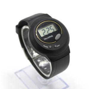 May include: Black digital talking watch with a round face and a black strap. The watch face displays the time and the word "TALKING". It has three buttons labelled "MODE" and "ADJ". The watch is displayed on a clear plastic stand.