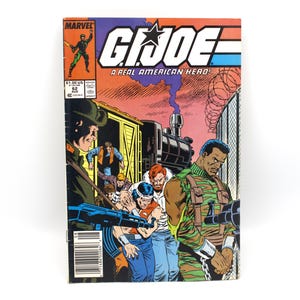 May include: A vintage G.I. Joe comic book with a vibrant cover. The cover features a dynamic illustration of soldiers, a train, and the text "G.I. Joe: A Real American Hero!" in bold letters. The comic is set against a colorful backdrop.