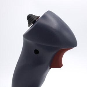 Puede incluir: Primer plano de un dispositivo port&aacute;til azul oscuro con un gatillo rojo y un bot&oacute;n negro. El dispositivo tiene una parte superior redondeada y un bot&oacute;n negro texturizado en la parte superior. El fondo es blanco.