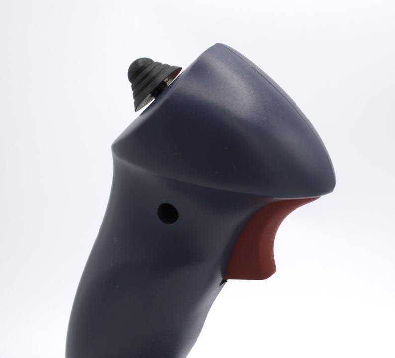 Puede incluir: Primer plano de un dispositivo port&aacute;til azul oscuro con un gatillo rojo y un bot&oacute;n negro. El dispositivo tiene una parte superior redondeada y un bot&oacute;n negro texturizado en la parte superior. El fondo es blanco.