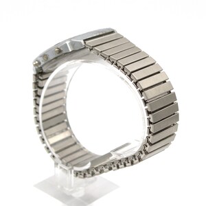 Peut inclure: Une montre-bracelet argent&eacute;e avec un cadran rectangulaire et un bracelet en m&eacute;tal flexible. Le bracelet est compos&eacute; de nombreux maillons rectangulaires. La montre est pr&eacute;sent&eacute;e sur un support transparent sur fond blanc.