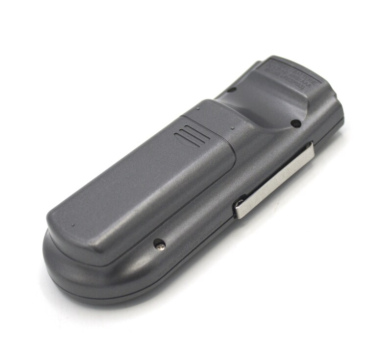 May include: A black remote control with a silver clip on the side. The remote has a textured surface and a small button on the top.