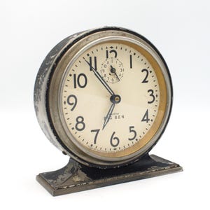 May include: A vintage silver-colored Westclox Big Ben alarm clock with black hands and a white face. The clock has a black base and a gold-colored rim around the face.