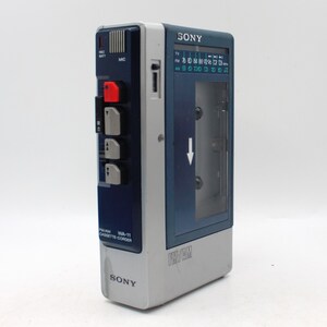 May include: A vintage Sony FM/AM cassette recorder, model WA-11, in a blue and gray color scheme. Features a clear cassette compartment, a radio dial, and control buttons. The recorder has the Sony logo on the front.