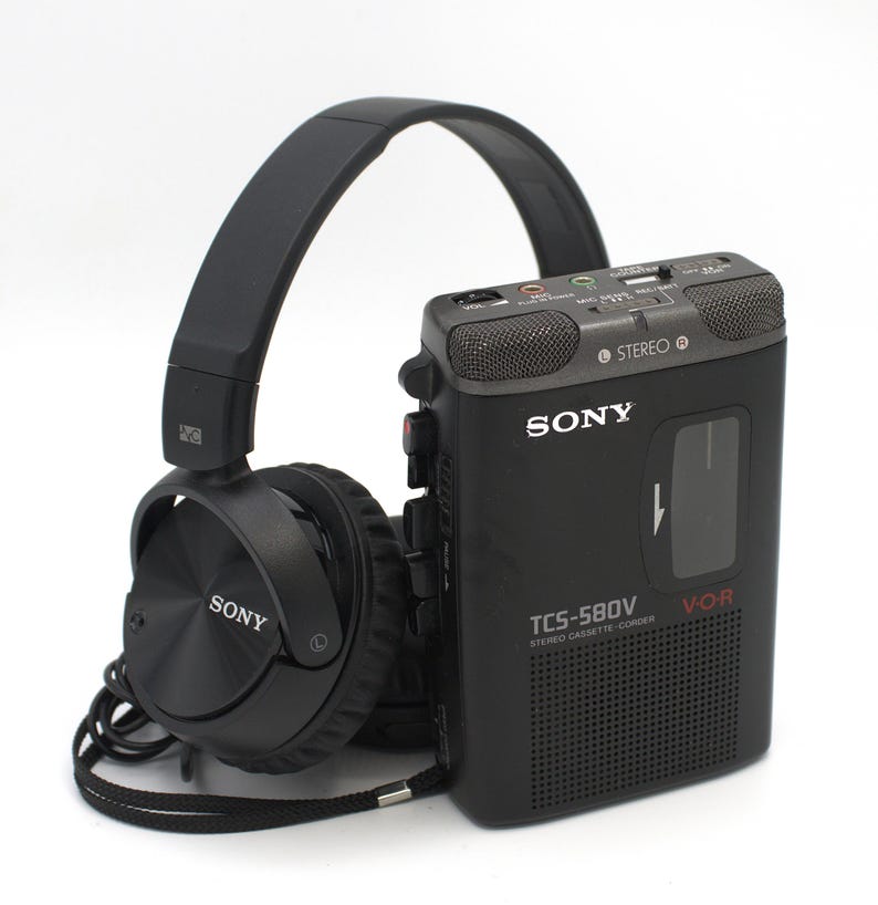 May include: A black Sony TCS-580V stereo cassette-corder with a pair of black Sony headphones. The cassette recorder has the Sony logo and the words "STEREO" and "V.O.R." printed on it. The headphones are connected to the recorder.