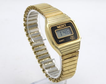 Vintage 1980s digital wristwatch LCD quartz display with light button polished gold tone finish elastic metal band black dial Merit 80s