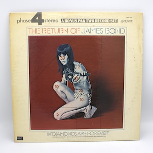 May include: Vintage vinyl record album cover for "The Return of James Bond." The cover features a woman holding a gun, with the text "Diamonds Are Forever." The album is a bonus pack two record set.