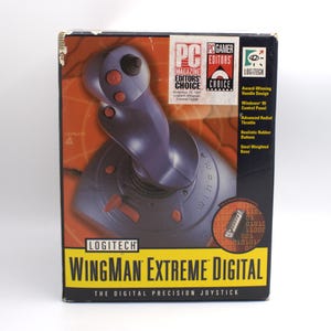 Puede incluir: Caja original del joystick Logitech WingMan Extreme Digital. La caja presenta un joystick morado con botones rojos, una base negra y el texto "WingMan Extreme Digital". La caja tiene un dise&ntilde;o amarillo y negro.