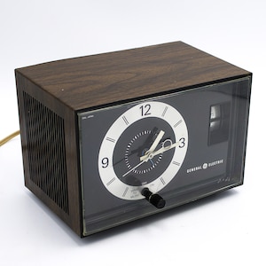 Vintage 1970s GE alarm clock radio AM receiver woodgrain black silver aluminum analog dial General Electric
