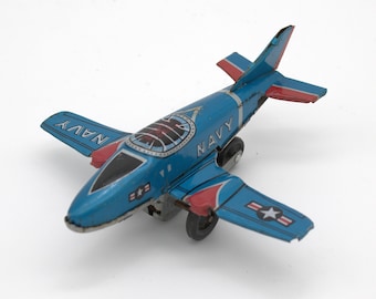 Vintage tin toy airplane US Navy military theme fighter jet motorized wheels stamped steel mid-century Japan