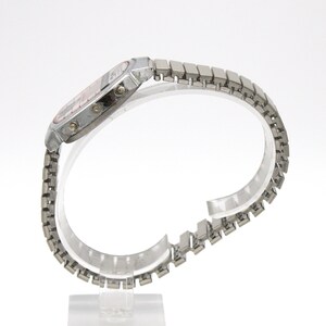 Peut inclure: Une montre-bracelet num&eacute;rique argent&eacute;e avec un cadran rectangulaire et un bracelet en m&eacute;tal &agrave; maillons. Le cadran de la montre a un affichage rouge. La montre est expos&eacute;e sur un support transparent sur fond blanc. La montre est de style vintage.