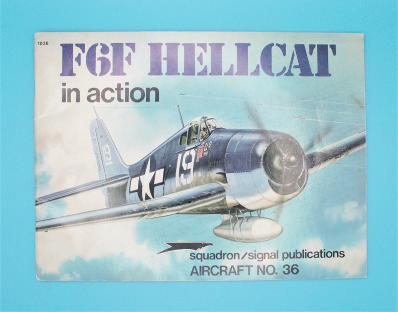 May include: A vintage book cover featuring a blue and white F6F Hellcat fighter plane in flight. The cover is titled "F6F Hellcat in action" and includes the text "Squadron/Signal Publications Aircraft No. 36".