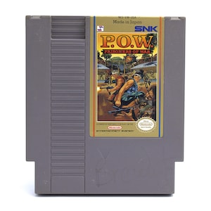 May include: A gray Nintendo Entertainment System (NES) cartridge for the game "P.O.W. Prisoners of War." The label features action-packed artwork with the game's title in bold yellow letters. The cartridge is marked "Made in Japan."