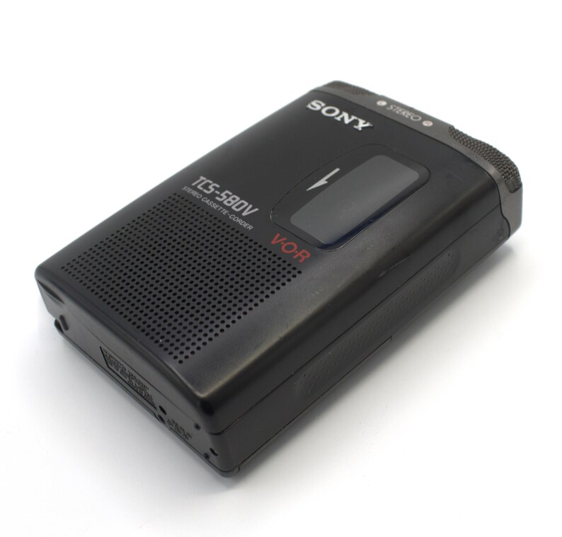 May include: Black Sony TCS-580V stereo cassette-corder. The portable recorder has a speaker grill, a large play button, and the word "SONY" printed on the top. The model number and "V-OR" are also visible. The device is on a white background.