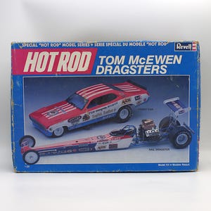 May include: A vintage Revell model kit box featuring "HOT ROD" and "TOM McEWEN DRAGSTERS." The box art showcases a red, white, and blue Funny Car and a Rail Dragster. The box is blue with red and white text.